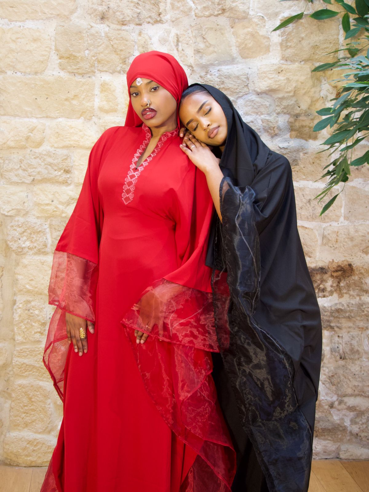 Deux Femmes portant la Hasna Dress noir et rouge – Deux robes longues noir et rouge avec une broderie africaine en organza, élégante