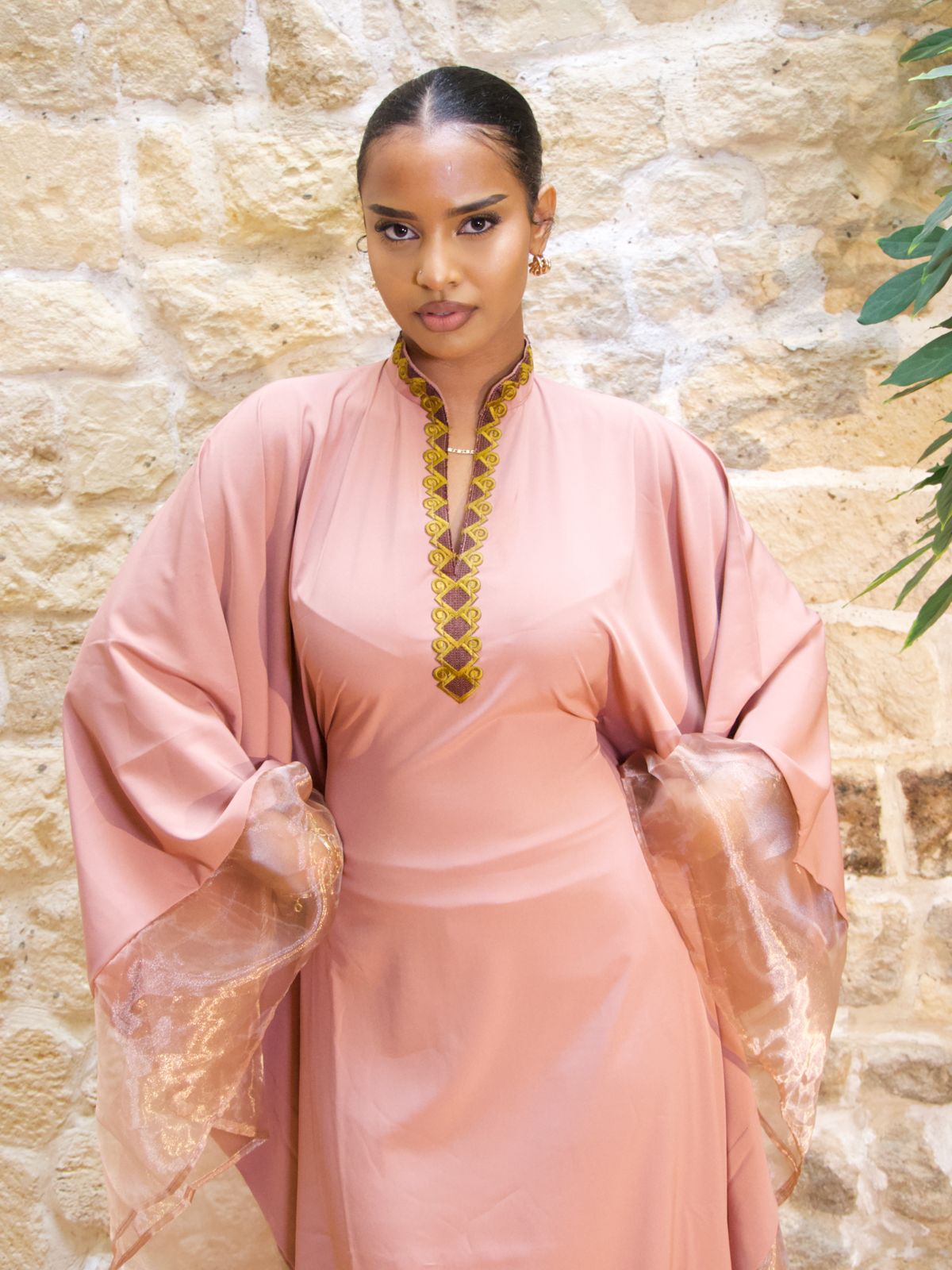 Femme portant la Hasna Dress rose avec une broderie marron et jaune – il s’agit d’une robe longue rose africaine en organza rose, élégante