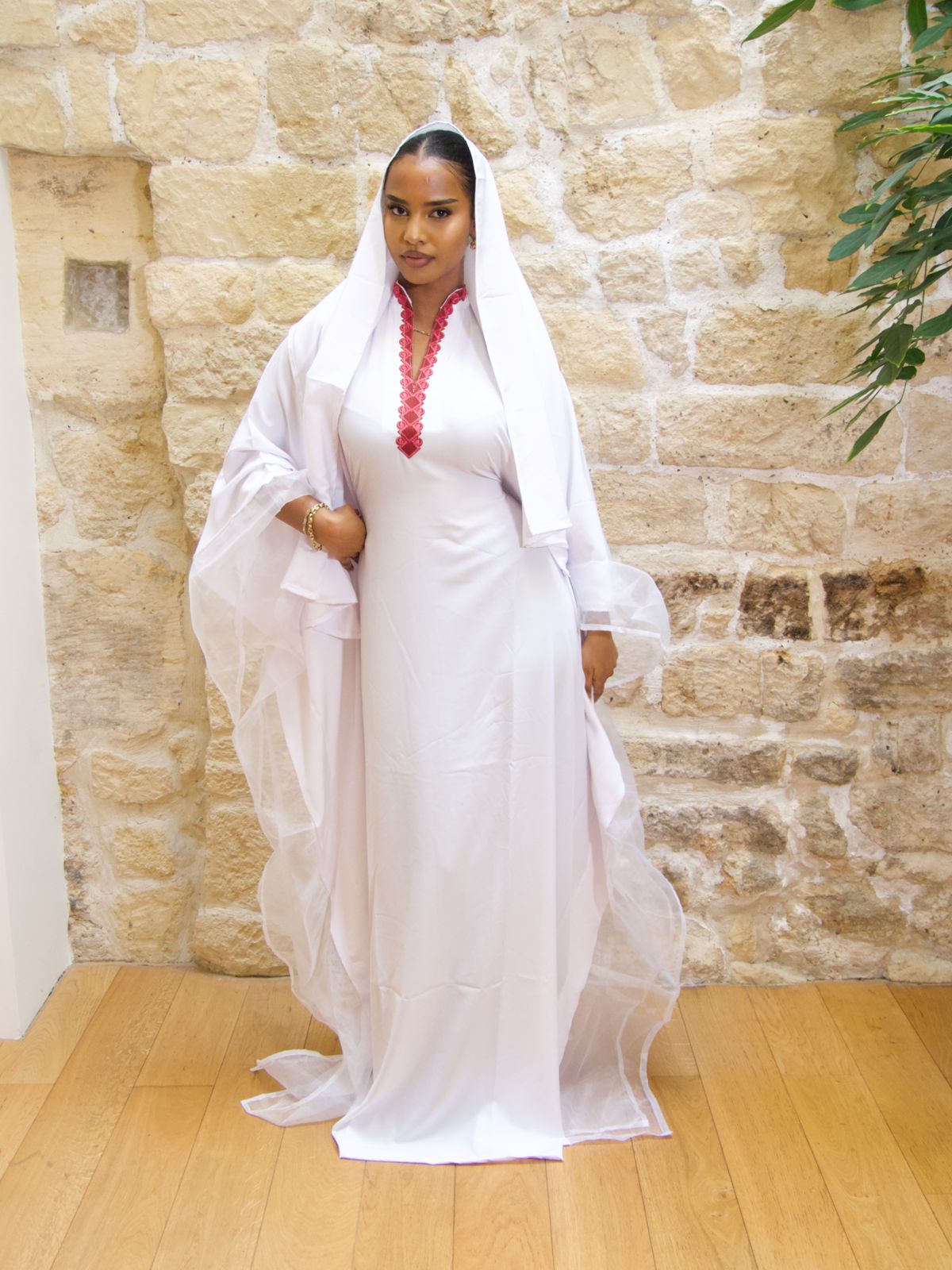 Femme portant la Hasna Dress blanche avec une broderie rose – il s’agit d’une robe longue blanche africaine en organza blanc, élégante