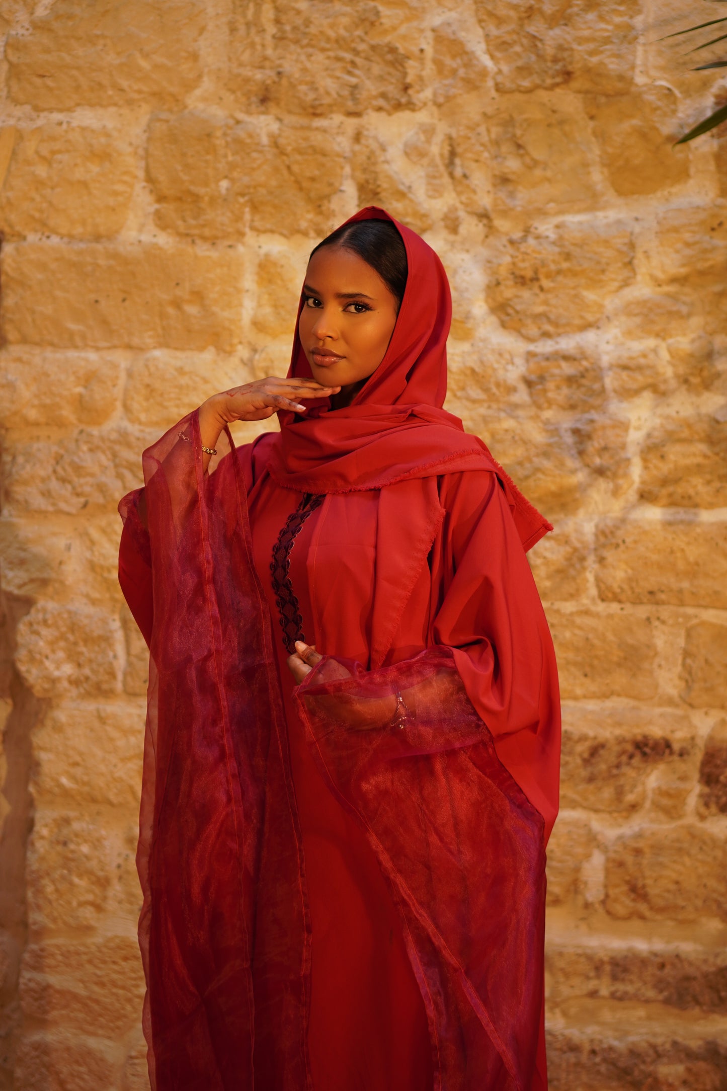Femme voilée portant la Hasna Dress rouge – robe longue rouge africaine en organza, élégante avec un foulard