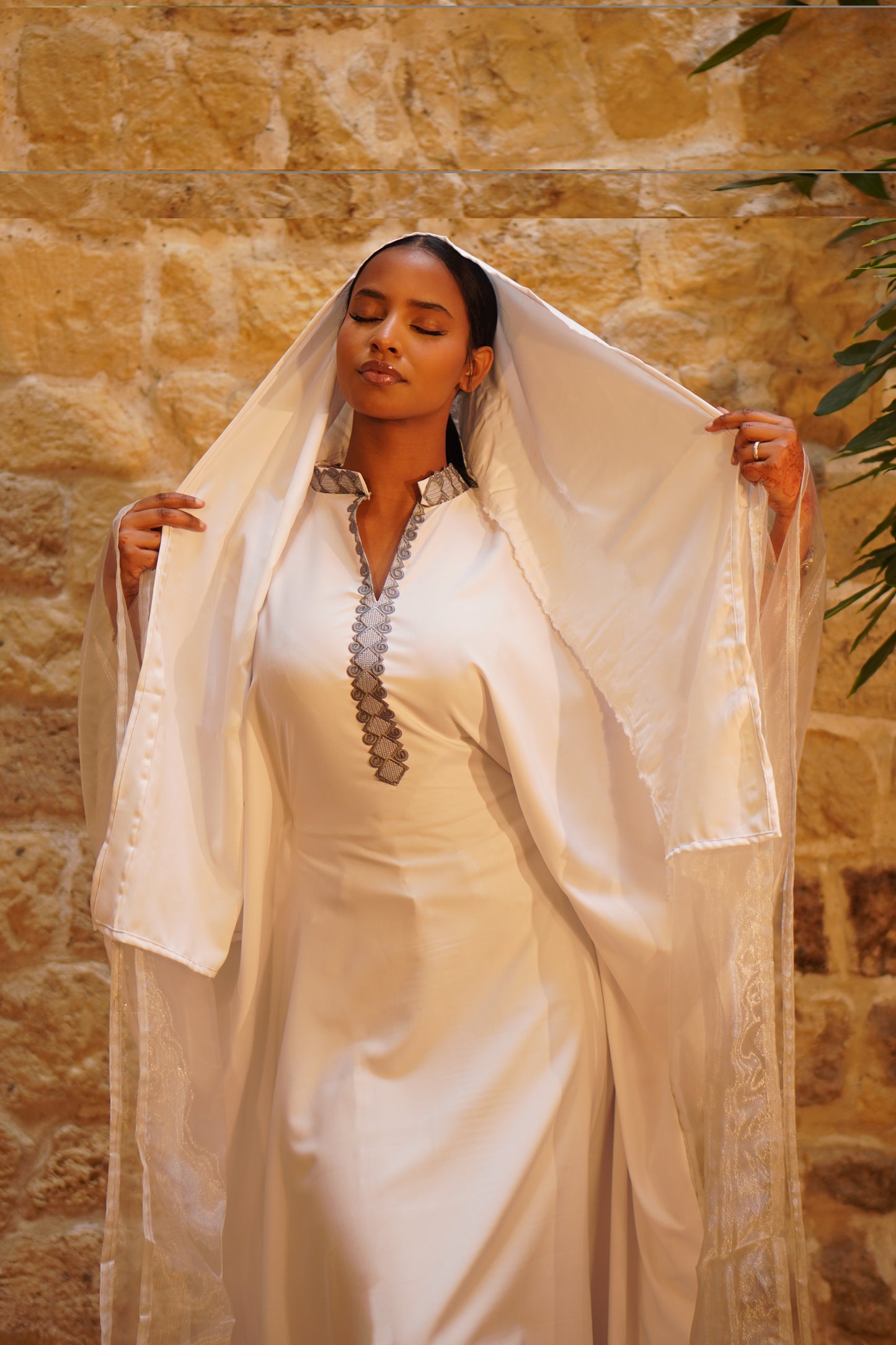 Femme portant la Hasna Dress blanche avec une broderie grise – il s’agit d’une robe longue blanche africaine en organza blanc, élégante